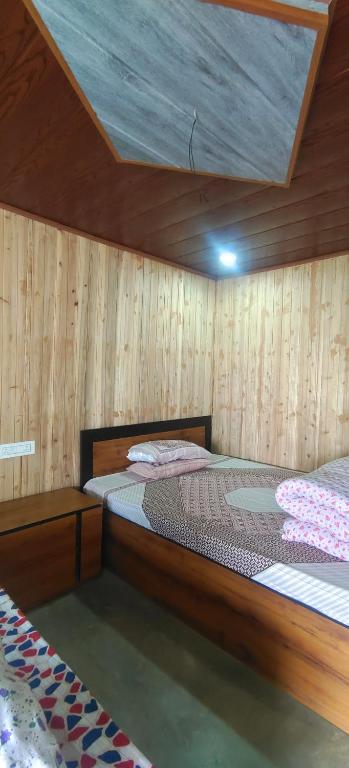 two beds in a room with wooden walls at Zero Points TheLaure Cottage in Ilām