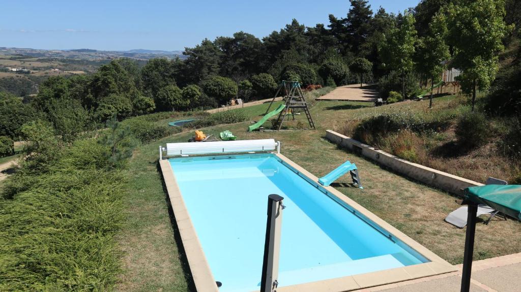 a swimming pool in a field with a playground at Gîte la Madeleine dans les gorges de la Loire in Dancé