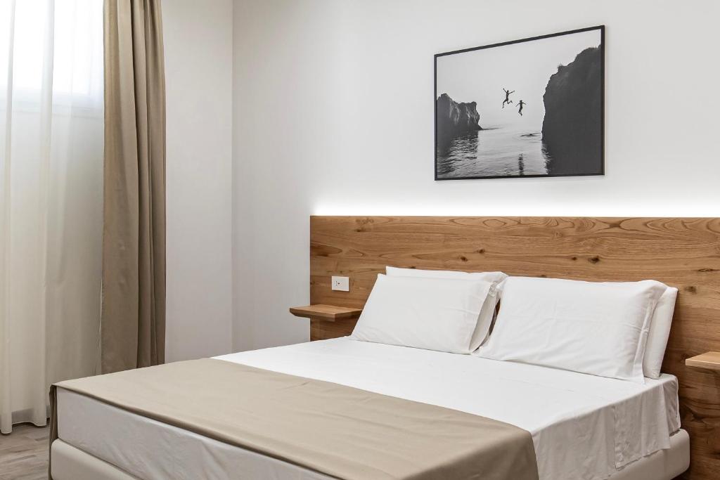 a bedroom with a bed with a wooden headboard at Sabbia Tropea Apartments and Rooms in Tropea