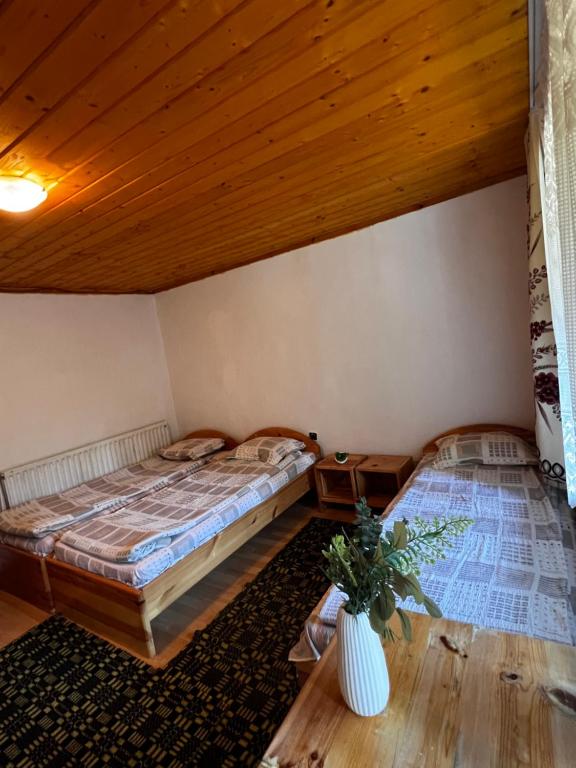 2 bedden in een kamer met houten plafonds bij Вила Еделвайс in Dobrinishte