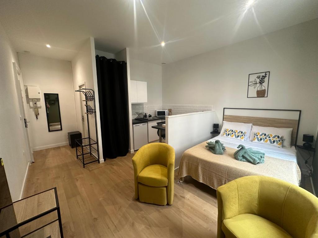 Cet appartement comprend une chambre avec un lit et deux chaises ainsi qu'une cuisine. dans l'établissement Lysbed - Studio Camélia - Angers, à Angers