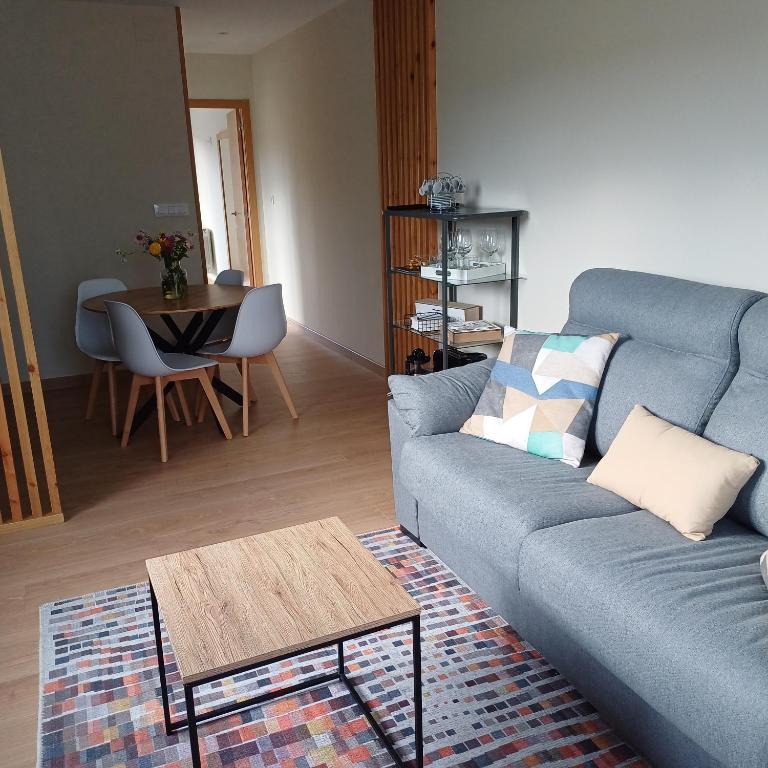 Una sala de estar con un sofá azul y una mesa. en Casa Da Ponte, en Lobios