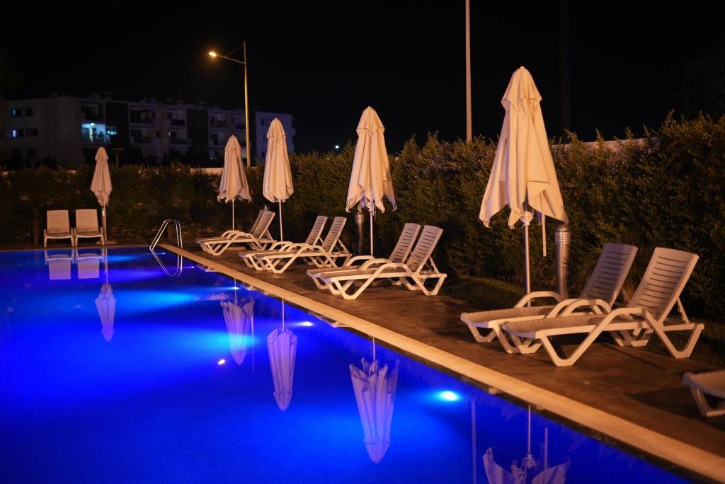 a group of chairs and umbrellas next to a swimming pool at night at Zephyr Agadir in Agadir