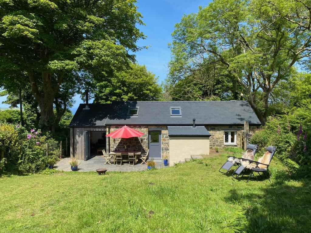 Una pequeña cabaña con una tienda de campaña roja en un patio. en Polly's Barn, Penrhyn, en Newport