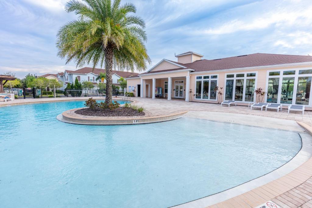 a swimming pool with a palm tree in front of a house at Elegant, Spacious 3bedroom Near Attractions Hot Tub Pool & Gym in Kissimmee