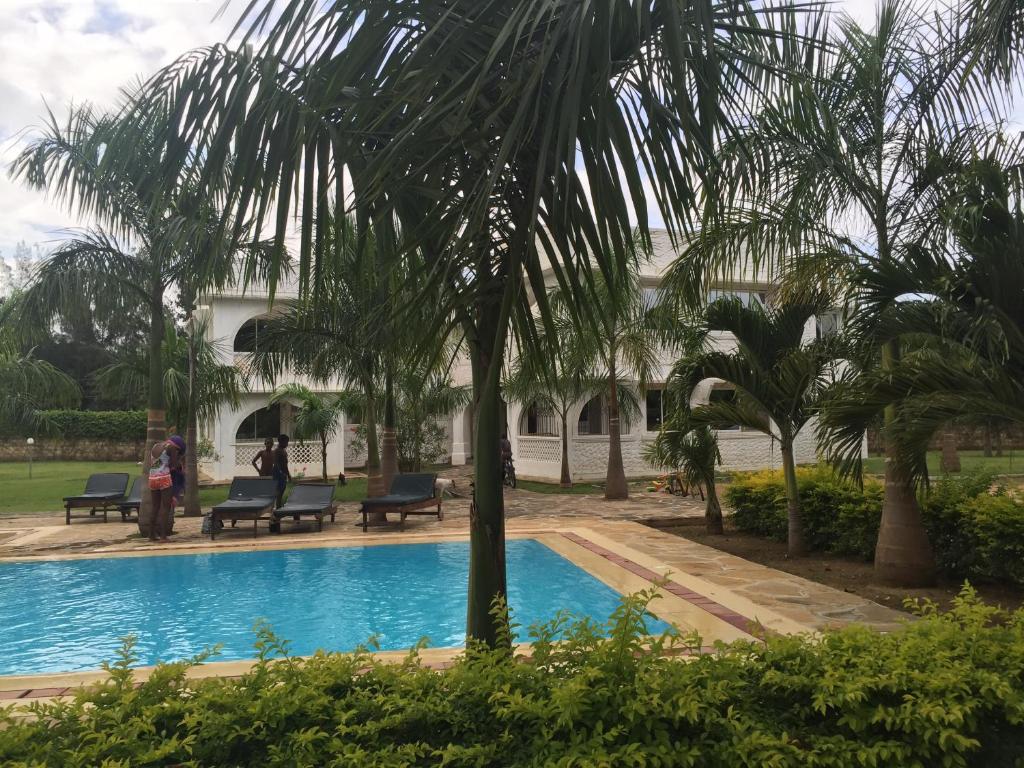 a palm tree next to a swimming pool at Royal Palms Mtwapa Apartments in Mtwapa