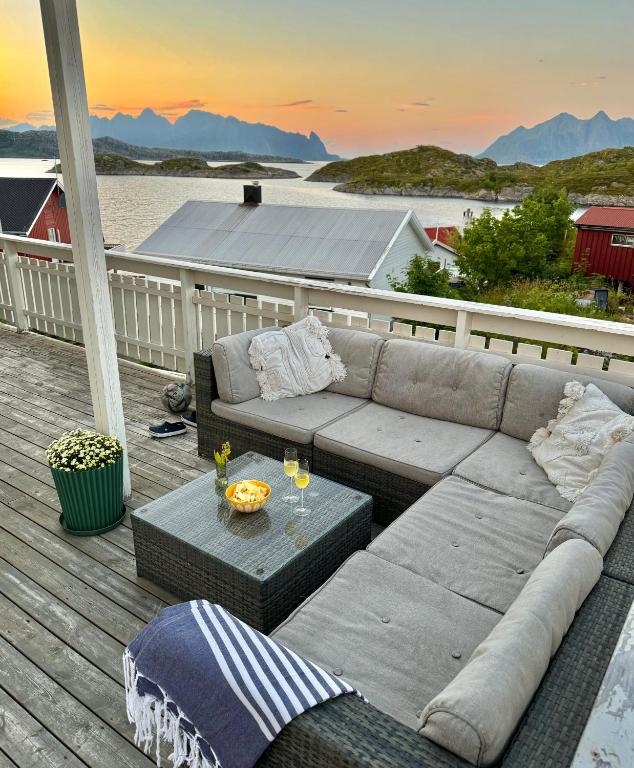 a couch and table on a deck with a view of the ocean at Idyllisk enebolig! in Svolvær