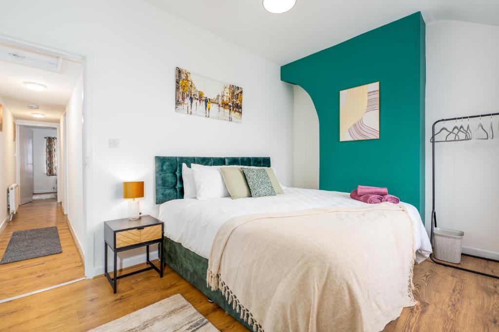 a bedroom with a large bed with a green headboard at Modern 3 bed perfect for contractors and families in Maltby