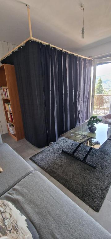 a living room with a black curtain and a glass table at Canapé lit "appartement partagé" en centre ville in Annemasse