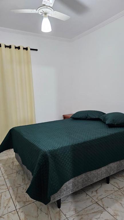 1 dormitorio con 1 cama verde y ventilador de techo en Miami Beach, en Praia Grande