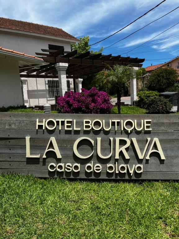 a sign for a hotel boutique la cuunta at LA CURVA Casa de Playa in Villa Gesell