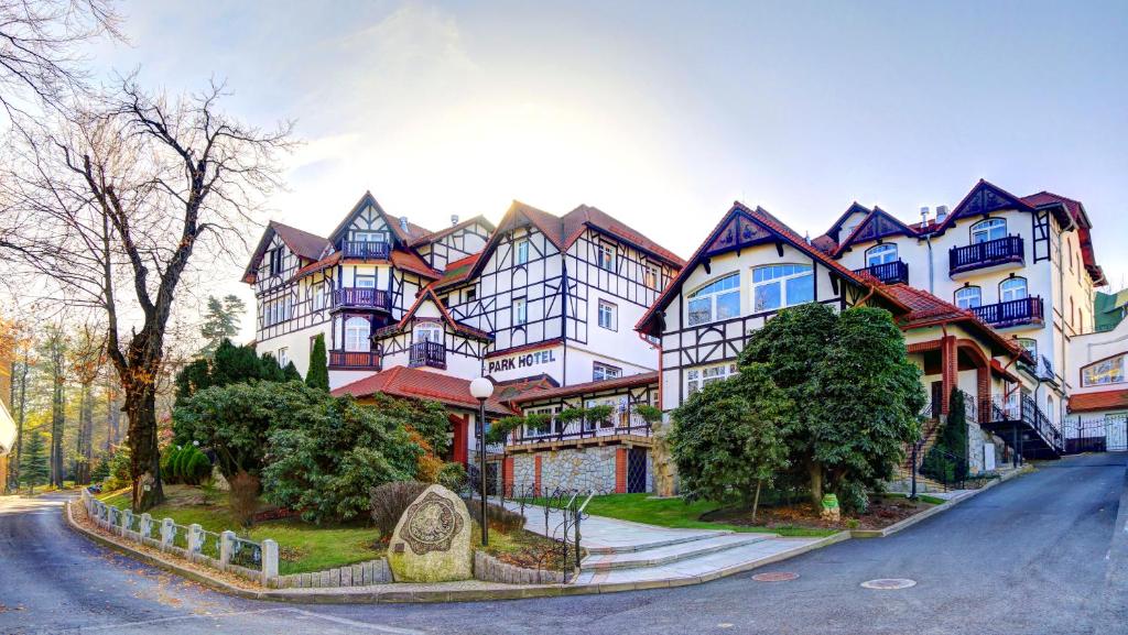 a large house on a street with trees in front of it at Park Hotel Kur & Spa in Świeradów-Zdrój