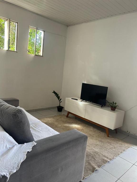 a white room with a bed and a tv at Lar sossego in Itabuna