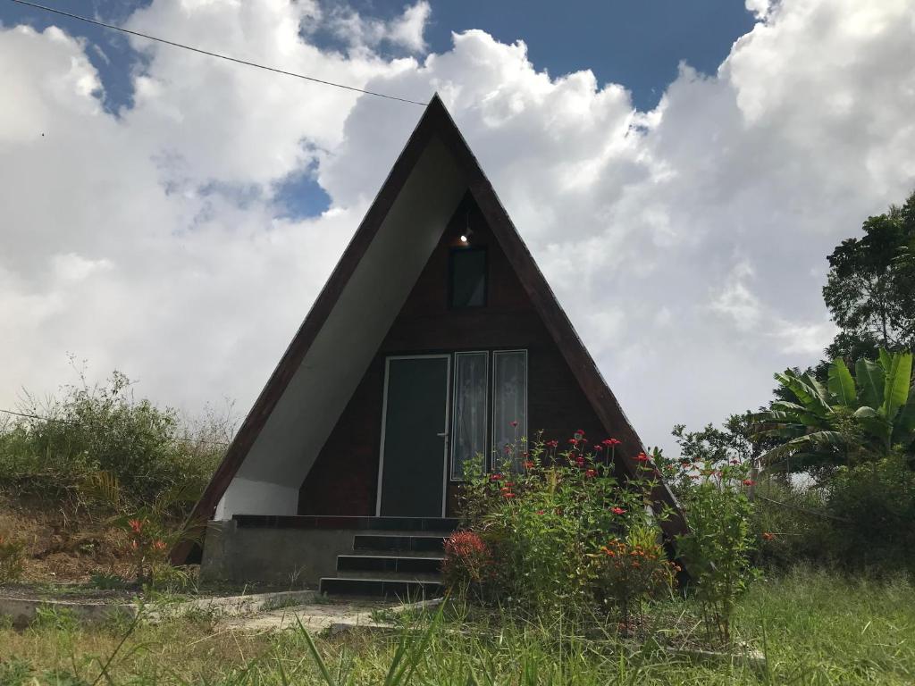 a small house with a pitched roof with a green door at Rinjani Eger Bungalow in Sembalun Lawang