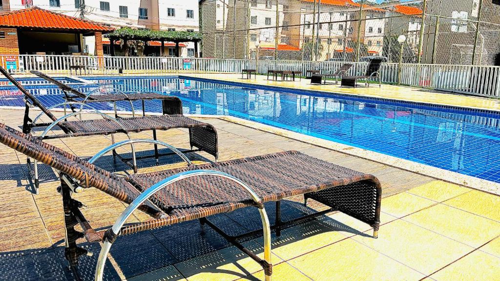 a large swimming pool with two benches next to it at Apartamento sofisticado com piscina e vista privativa in Ilhéus