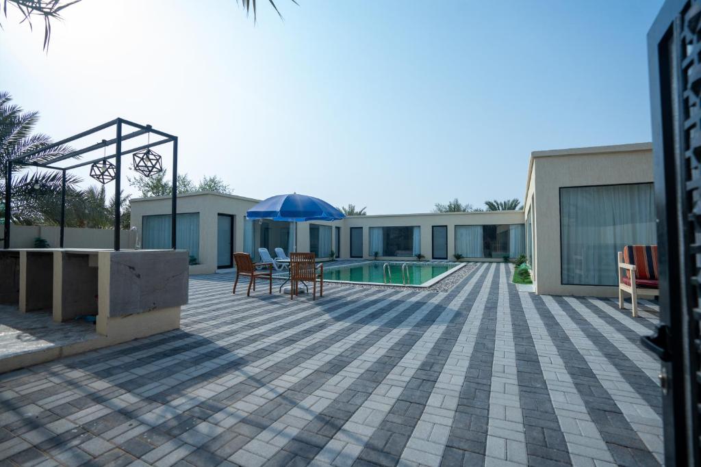 patio con tavolo e ombrellone blu di Farm Al Medfek a Ras al Khaimah