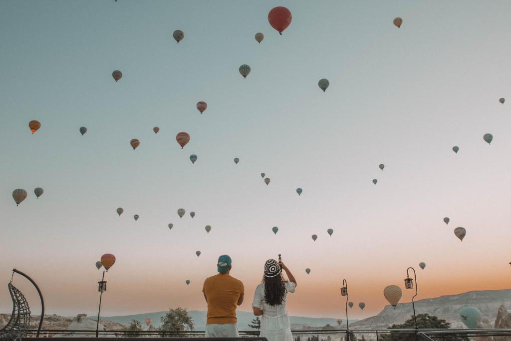 Una pareja mirando globos aerostáticos en el cielo. en Turan Cappadocia Cave, en Göreme