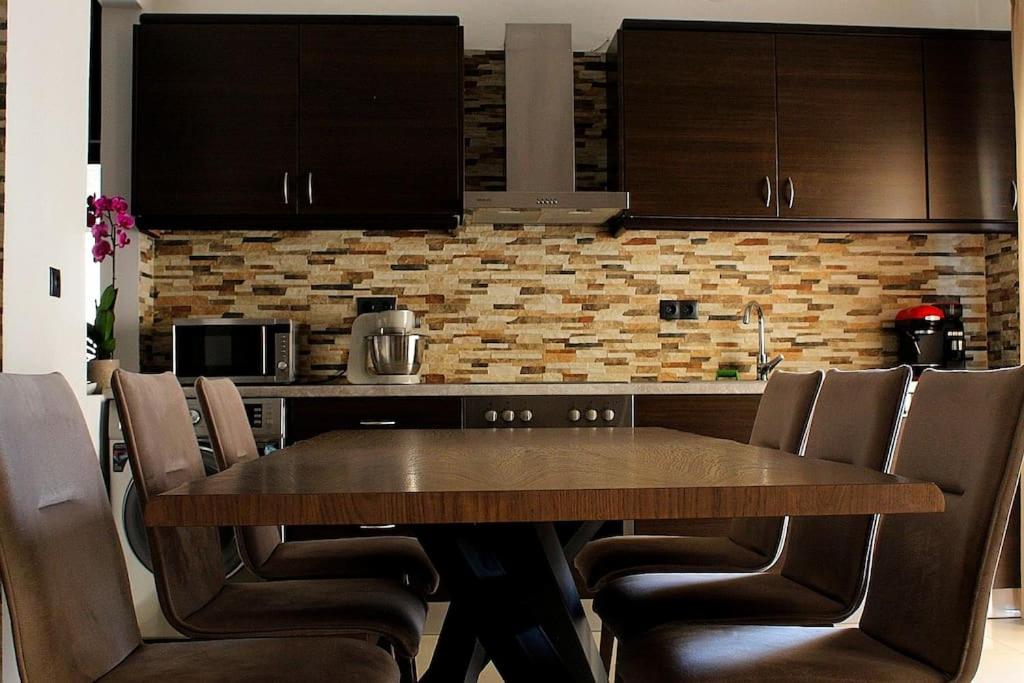 Una cocina con una mesa de madera y gabinetes marrones. en Diatza, en Rodas