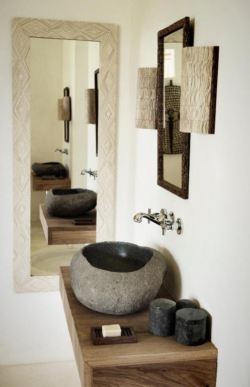 a bathroom with a stone sink and two mirrors at Qambani Luxury Resort in Michamvi
