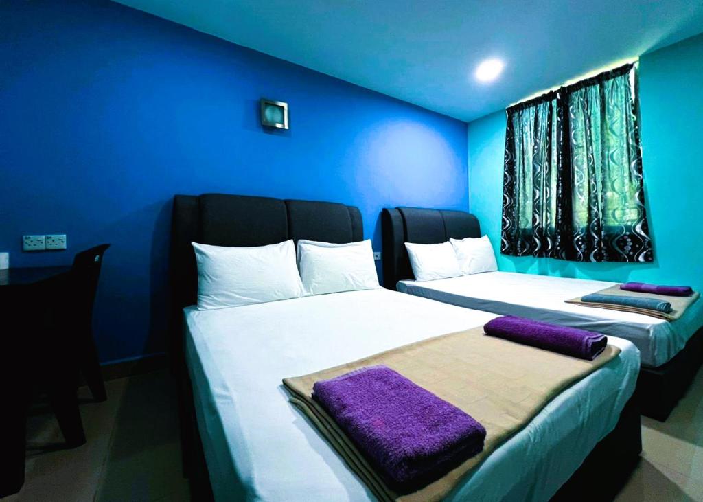 two beds in a room with blue walls at Puchong Business Hotel @ Putrajaya in Puchong