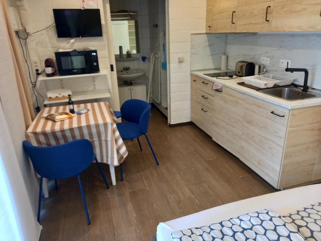 a small kitchen with a table and blue chairs at Studio Ceder 1 in Houthalen-Helchteren