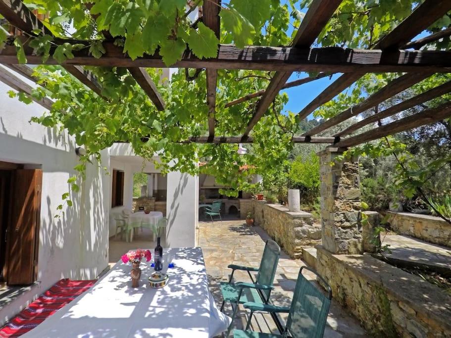 a table and chairs under a wooden pergola at Klea's House Skopelos in Skopelos Town