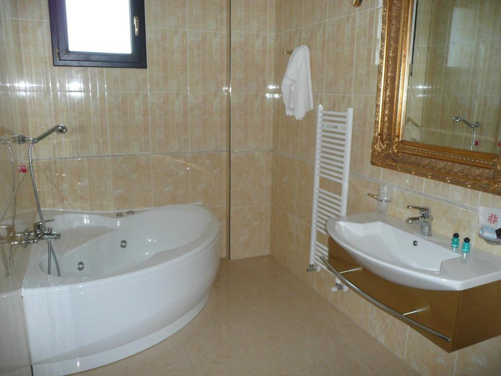 Un baño con bañera, lavabo y espejo. en Hotel Riva Del Sole, en Porto Cesareo