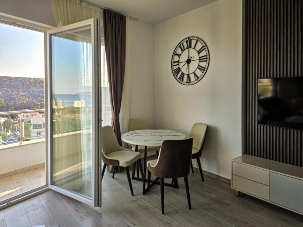 comedor con reloj, mesa y sillas en Juzni Horizont Apartments, en Sutomore