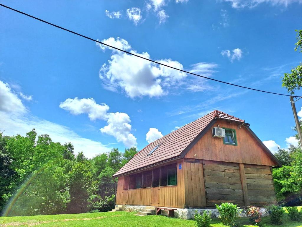a wooden barn with a roof on a field at Bakina iža in Duga Resa