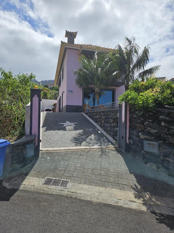 a pink house with a palm tree in front of it at Casa da Palmeira in Machico