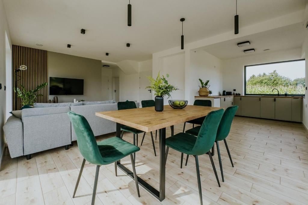 a kitchen and dining room with a wooden table and green chairs at Apartamenty u Cherubinów in Nałęczów