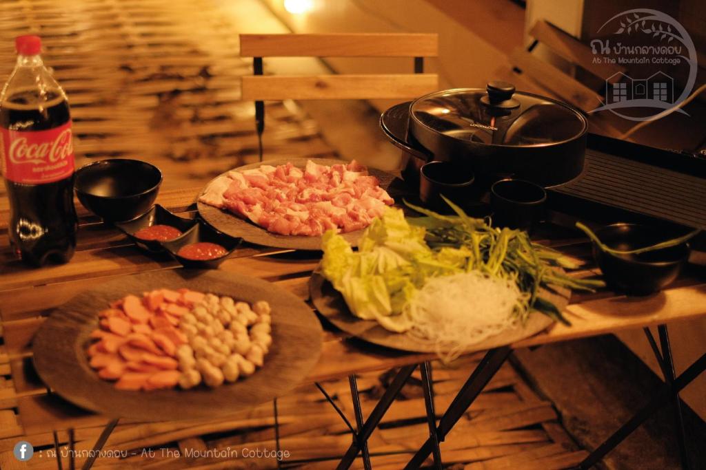 une table en bois avec des assiettes de nourriture dessus dans l'établissement At The Mountain Cottage, Tiny Home at Doichang with Hot tub Included Breakfast and Dinner, à Ban Huai Khai
