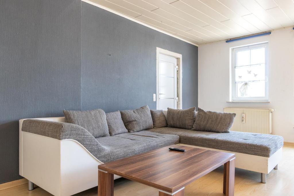 a living room with a couch and a wooden table at Arbeitnehmerunterkunft 6 Personen mit großer Terrasse in Sulzheim