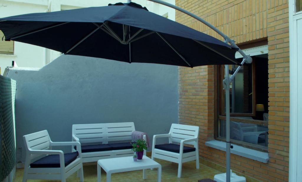 a black umbrella and two chairs and a table and chairs at Riojania El Vino in Calahorra