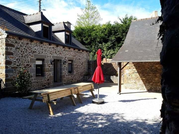un banc et un parasol devant un bâtiment dans l'établissement Maison 6 personnes en Bretagne, à Gicquel