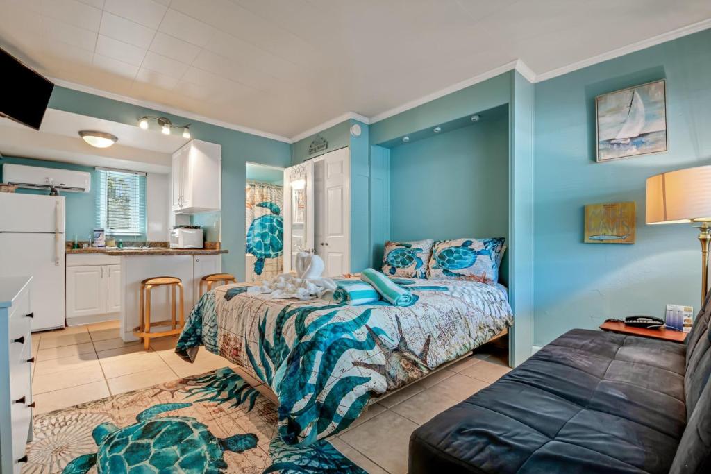 a bedroom with blue walls and a bed and a kitchen at Tropic Terrace Suite #4 - Beachfront Resort in St Pete Beach