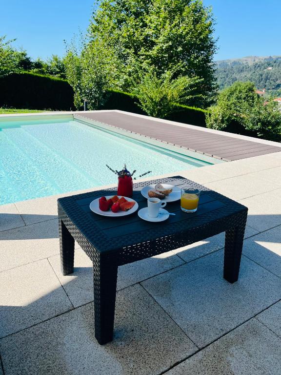 a table with food on it next to a pool at Basto Village House - Eco Smart Luxury Villa in Cabeceiras de Basto