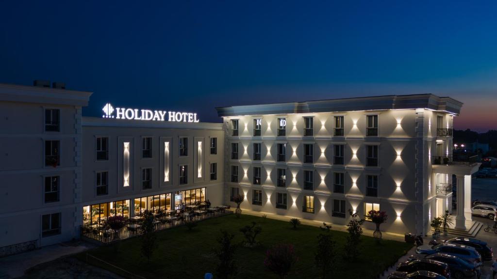 a hotel with a lit up building at night at Holiday Hotel in Tirana