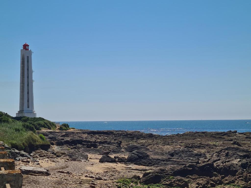 un phare sur une rive rocheuse à côté de l'océan dans l'établissement Apt 4 personnes, Résidence Atoll, piscine & vue sur la mer, à Les Sables-dʼOlonne