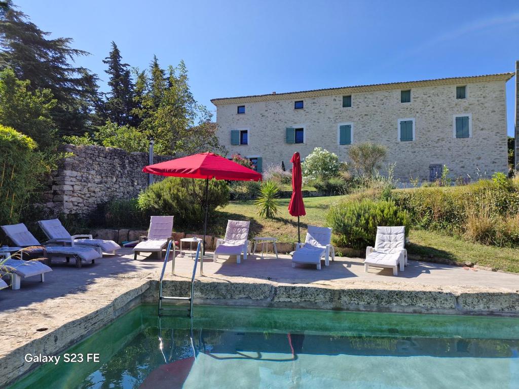 une piscine avec des chaises et un parasol et un bâtiment dans l'établissement Mas de 