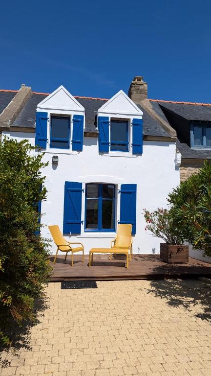 une maison blanche avec des fenêtres bleues et 2 chaises dans l'établissement Ti Maen, à Arzon