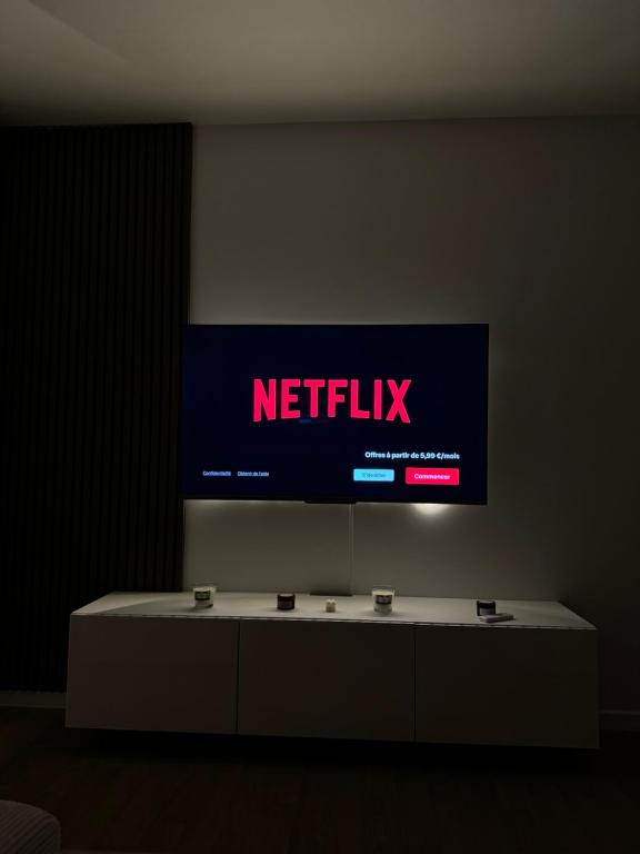 Elle comprend une télévision murale avec une table blanche. dans l'établissement Cosy T2 au porte de Paris au pied du metro L9, à Montreuil