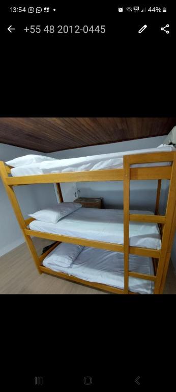 uma imagem de um beliche com lençóis brancos em Hostel Papai em Florianópolis