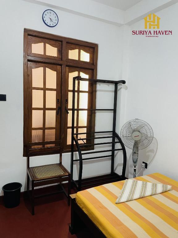 a room with a bed and a chair and a clock at Suriya Haven Homestay in Badulla