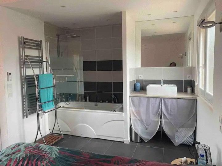 a bathroom with a tub and a sink and a mirror at Chambre tout confort in Saint-Nazaire