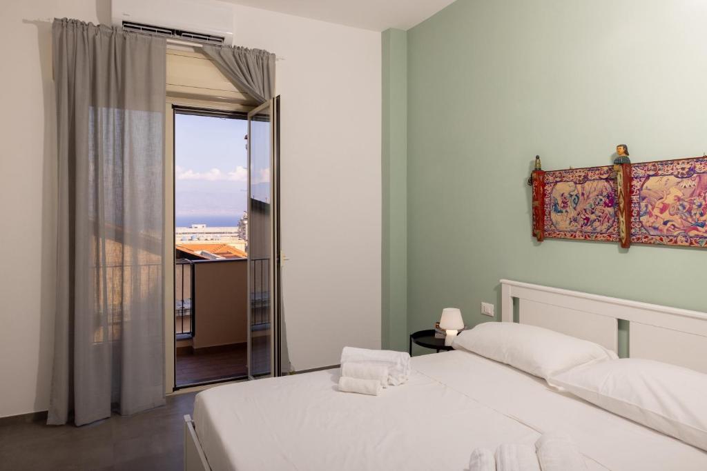 a bedroom with two white beds and a balcony at Cariddi in Messina