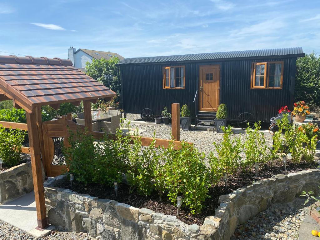 a tiny house in a garden with a stone wall at Carlingford Glamping Hut in Rathcor Lower