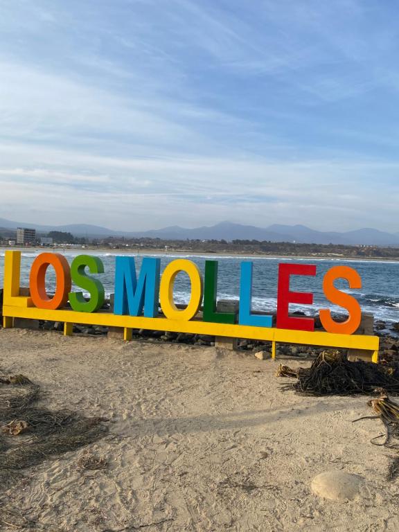 a sign on a beach with the words losumes at Departamento frente a la playa en Los Molles in Los Molles