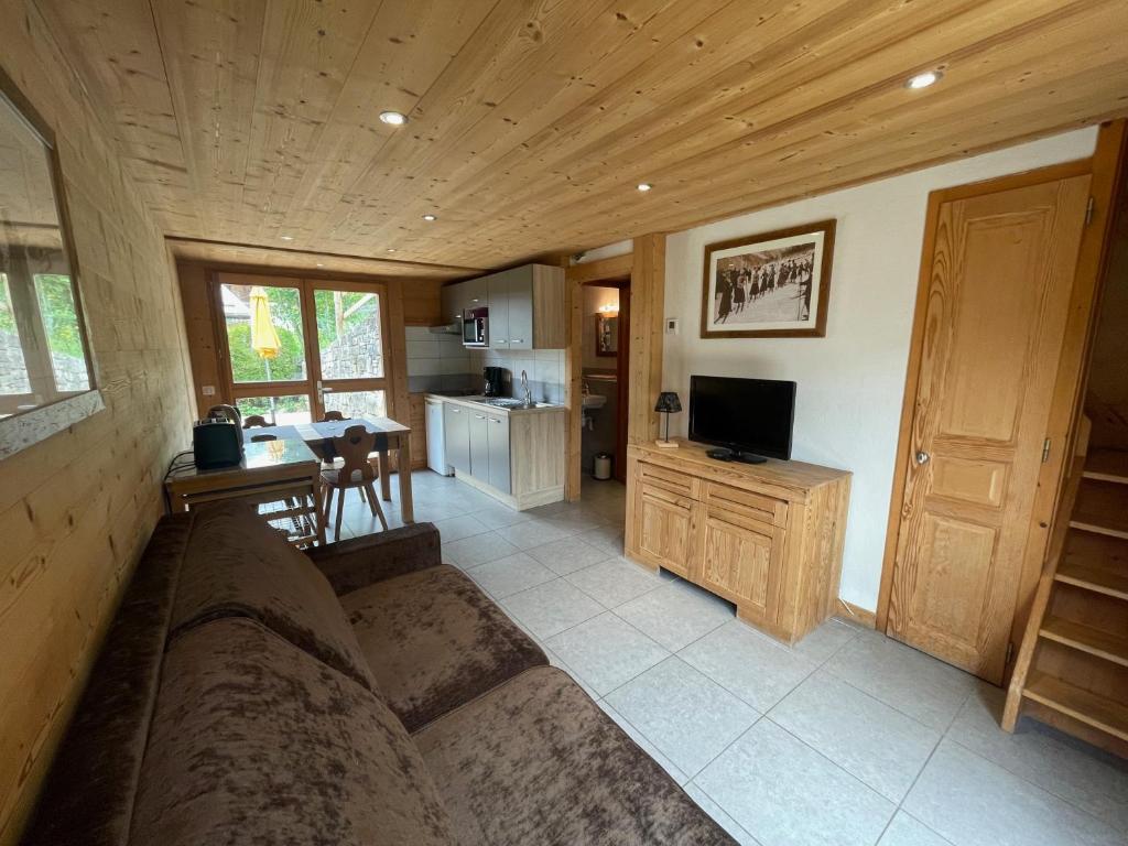 Una sala de estar con un sofá y una cocina. en Chalet Aravis, en Le Grand-Bornand