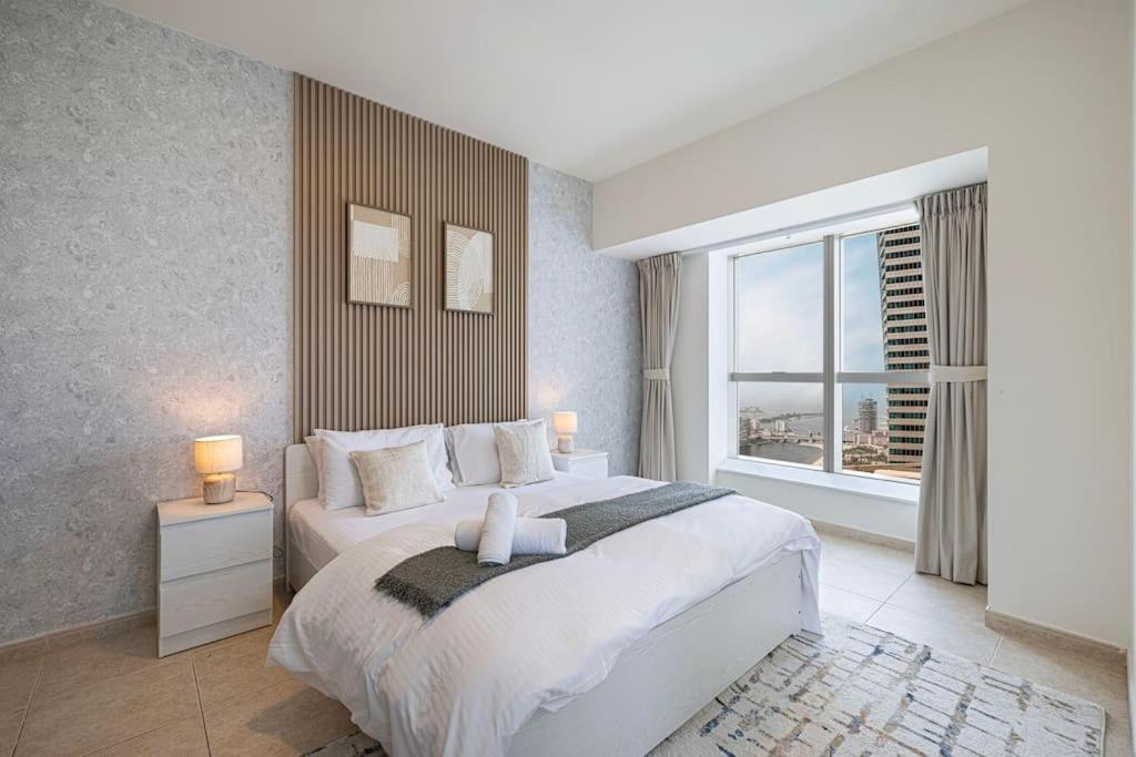 a bedroom with a large bed and a large window at Lux 2BR with Sea Views in Marina in Dubai